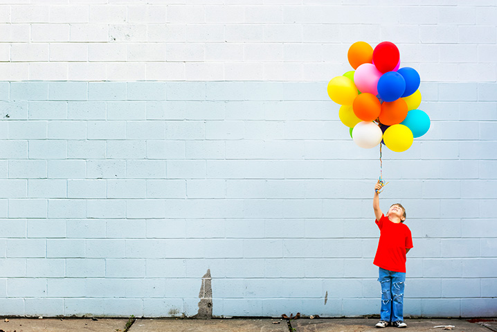Criança segurando balões.