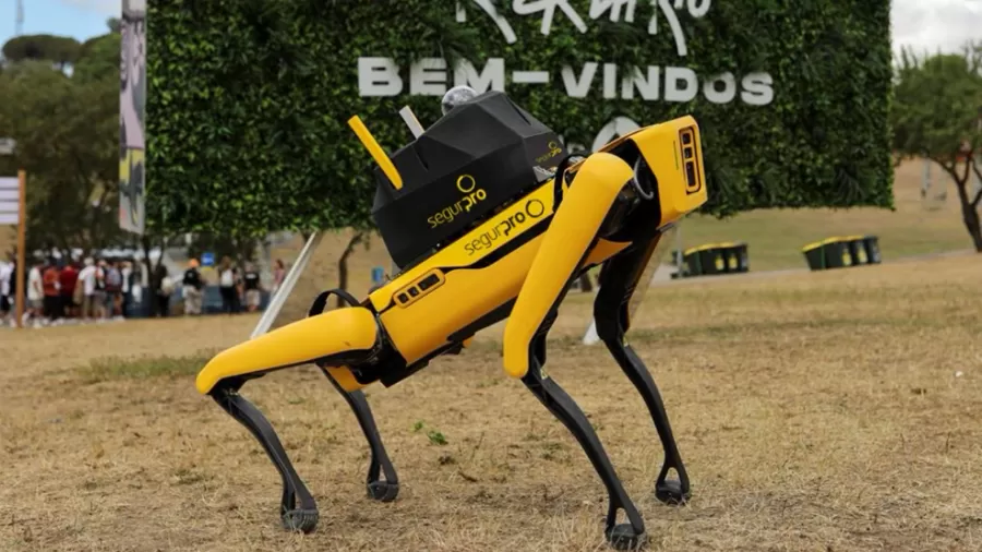 Fotografia colorida do cão-robô Yellow no gramado do Rock in Rio. O robô é amarelo e possui articulações parecidas com a de um cachorro. 