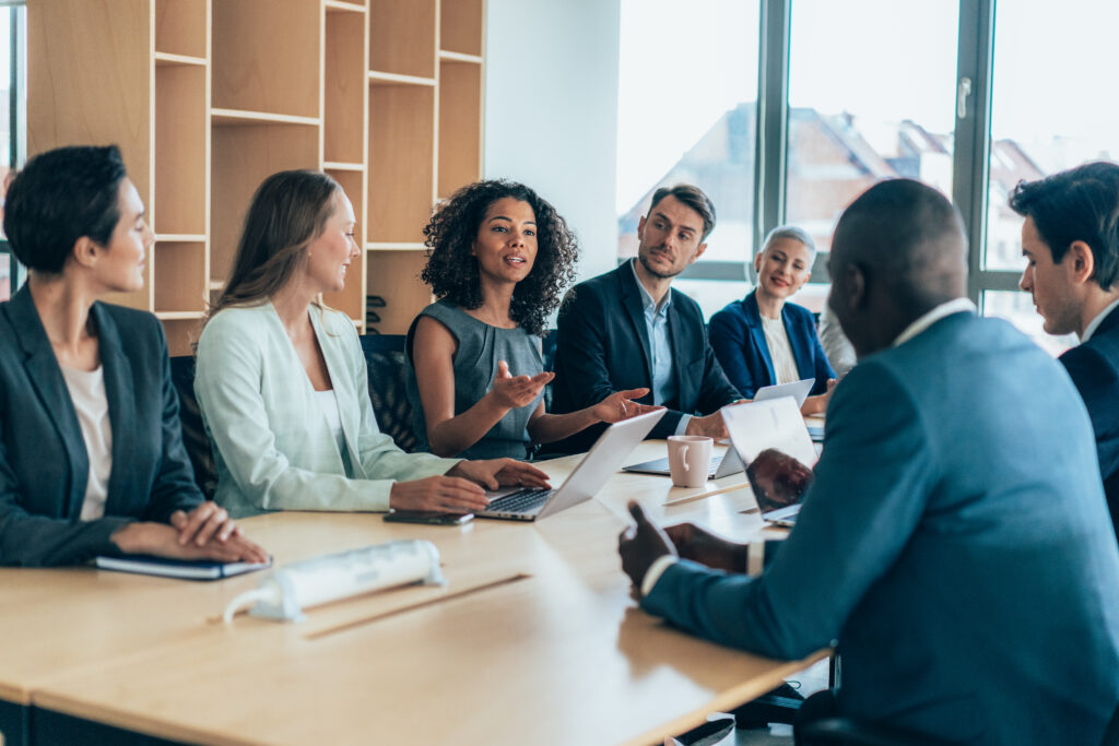 Grupo multiétnico de empresários sentados juntos e tendo uma reunião no escritório.